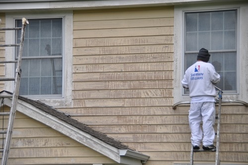 Painter refreshing a cedar siding home and home staining
