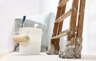 Paint bucket, brush, and ladder in background