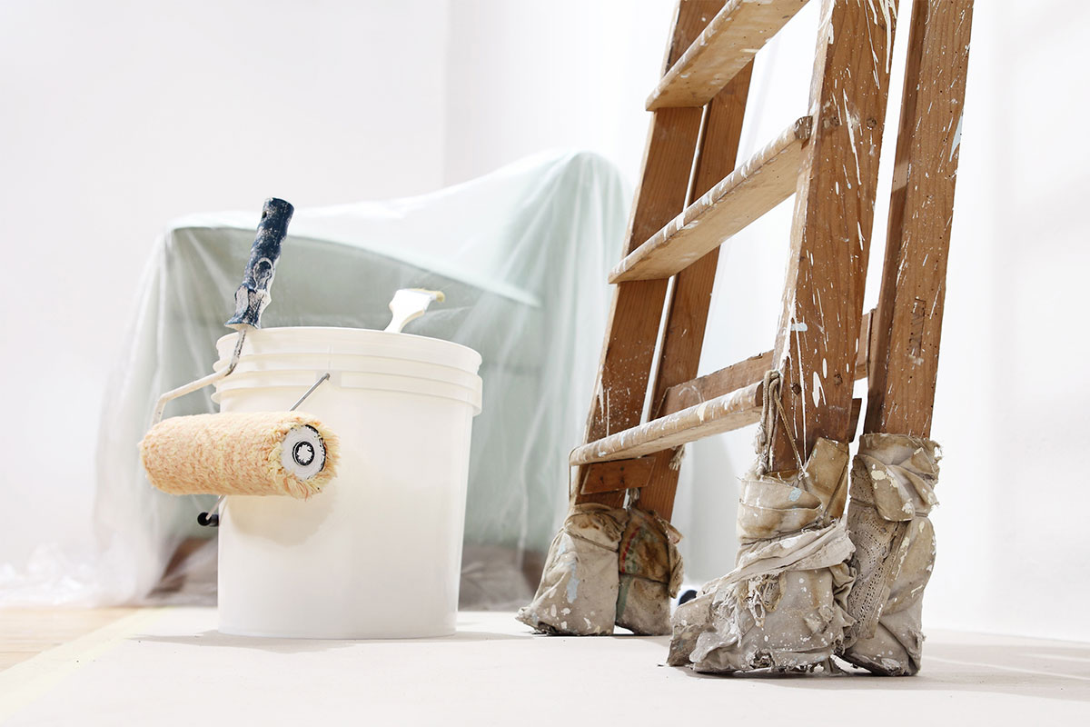 Paint bucket, brush, and ladder in background
