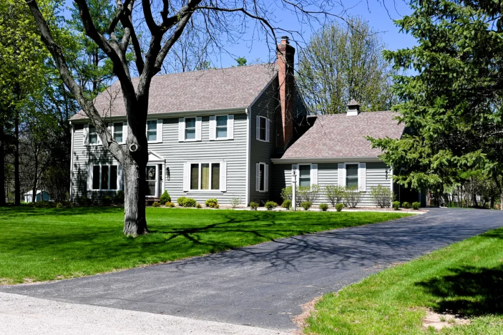 Exterior painting project on Bark River Ct in Delafield WI featuring gray siding, white trim, shutters, and a wooded Lake Country setting.