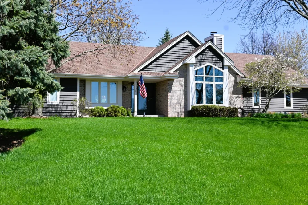 Exterior painting project on Alta Vista Dr in Sussex WI featuring refreshed siding, white trim, stone accents, gables, and a green front lawn.