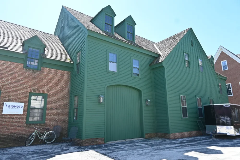 Exterior painting project on Pamelia St in Delafield WI featuring green siding, matching trim, dormers, brick accents, and a large arched entry door.