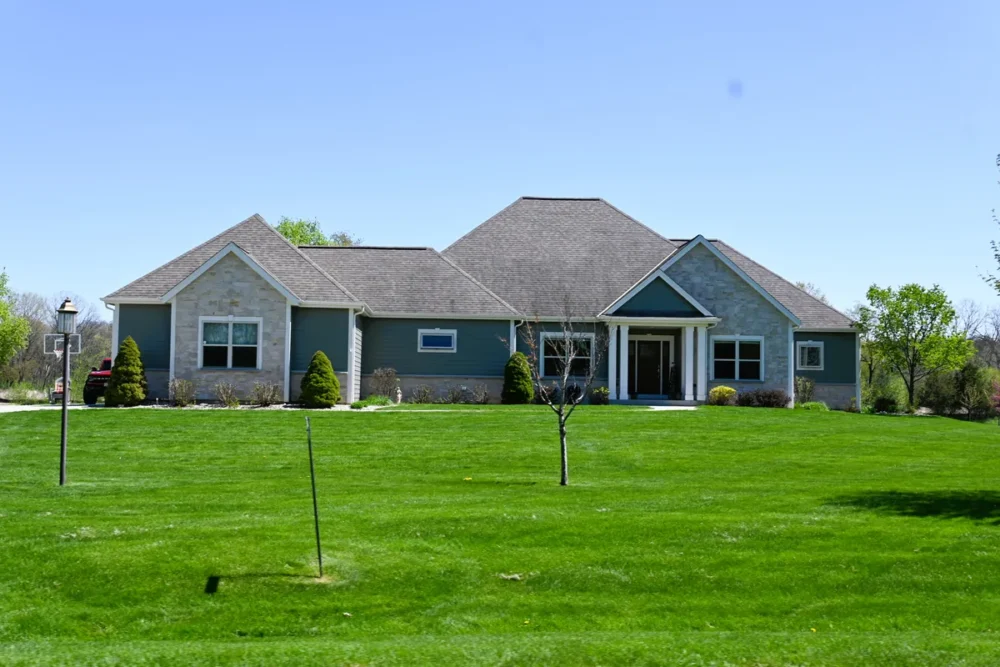 Exterior painting project on Ravinia View Ln in Oconomowoc WI featuring refreshed siding, crisp trim, stone accents, gable details, and a large green lawn.