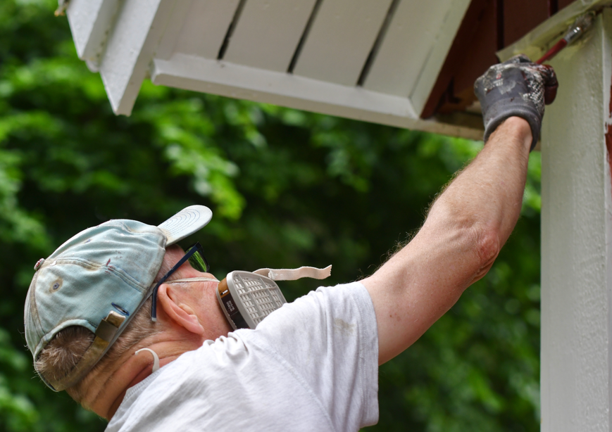 Exterior painter completing detailed trim work on a Muskego home