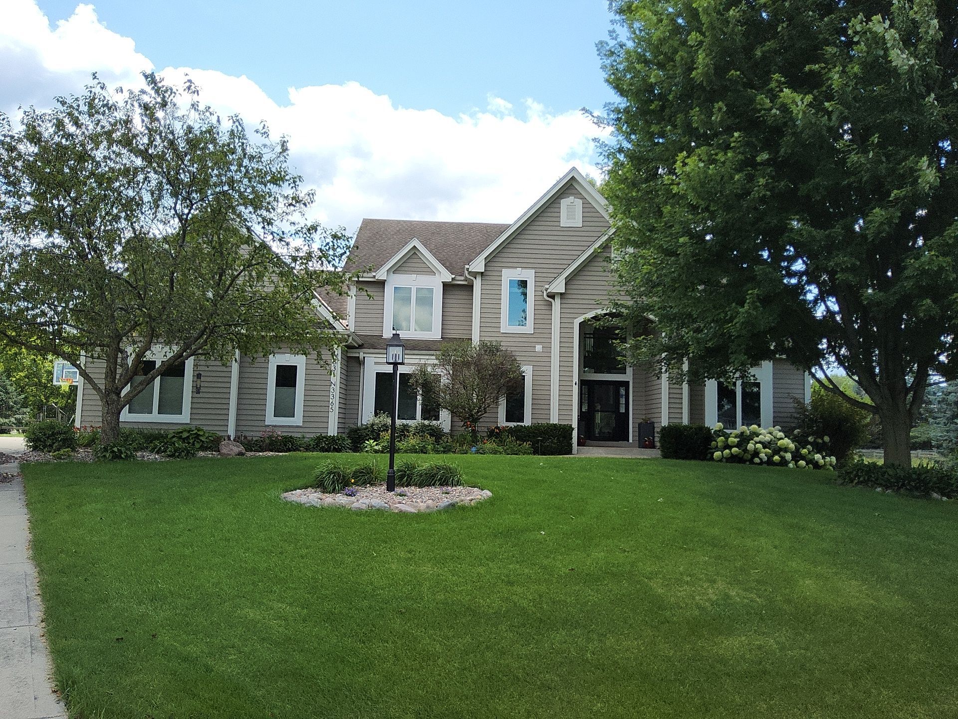 Nashotah home with taupe siding, white window trim and a dark front entry
