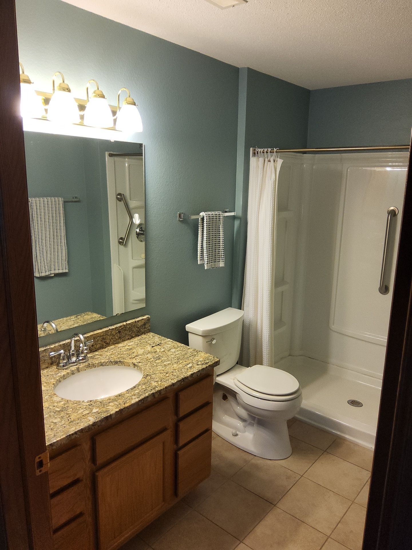 Blue-green bathroom walls with a white shower enclosure in Nashotah