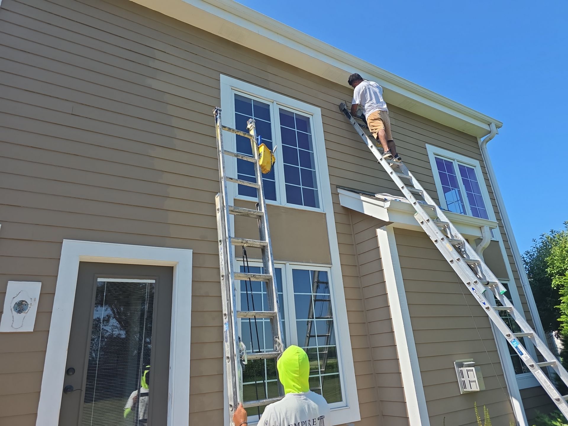 Two Empire crew members working on exterior siding and trim