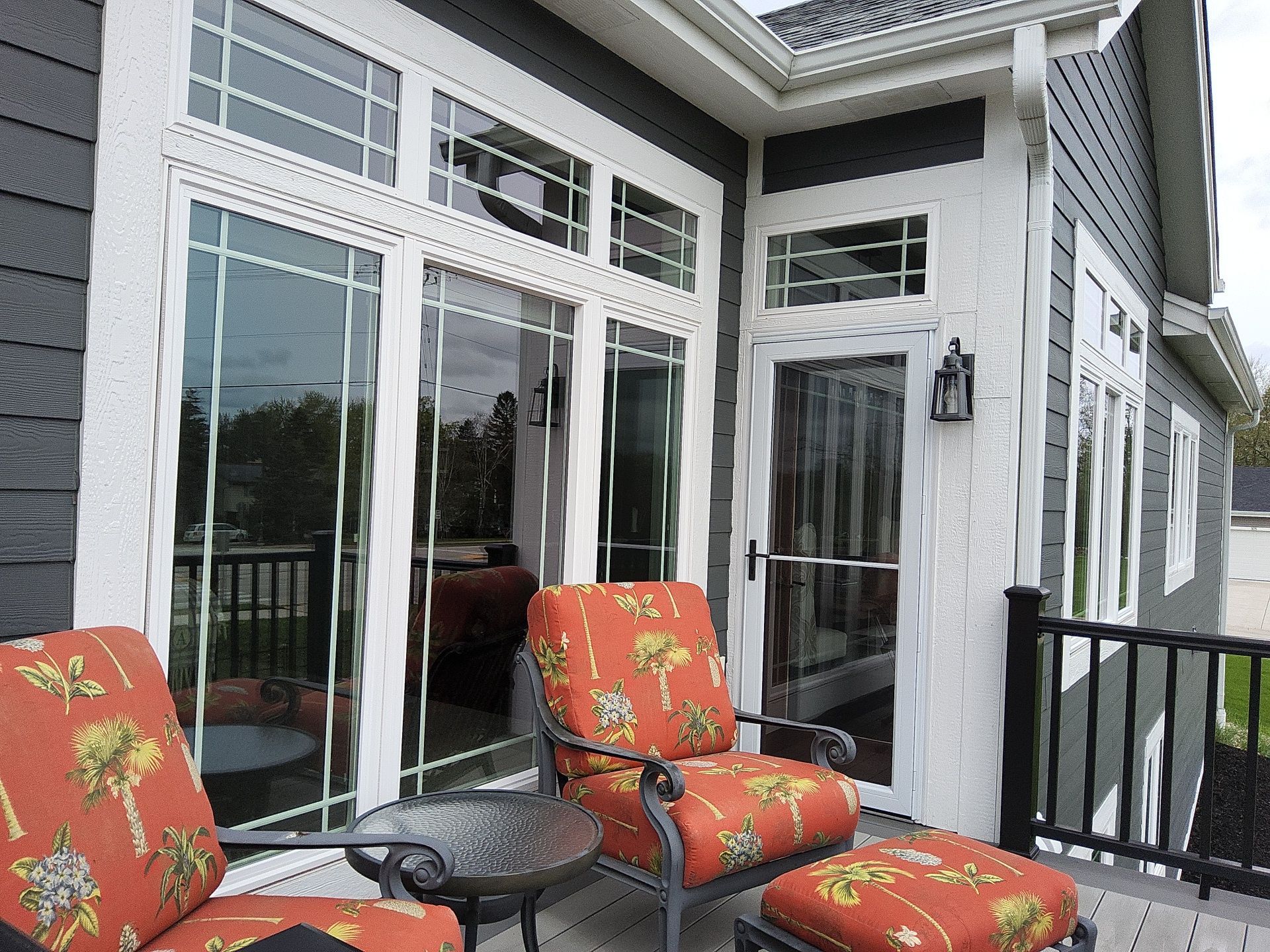 Deck seating beside white-trimmed windows and a patio door in Wales, Wisconsin