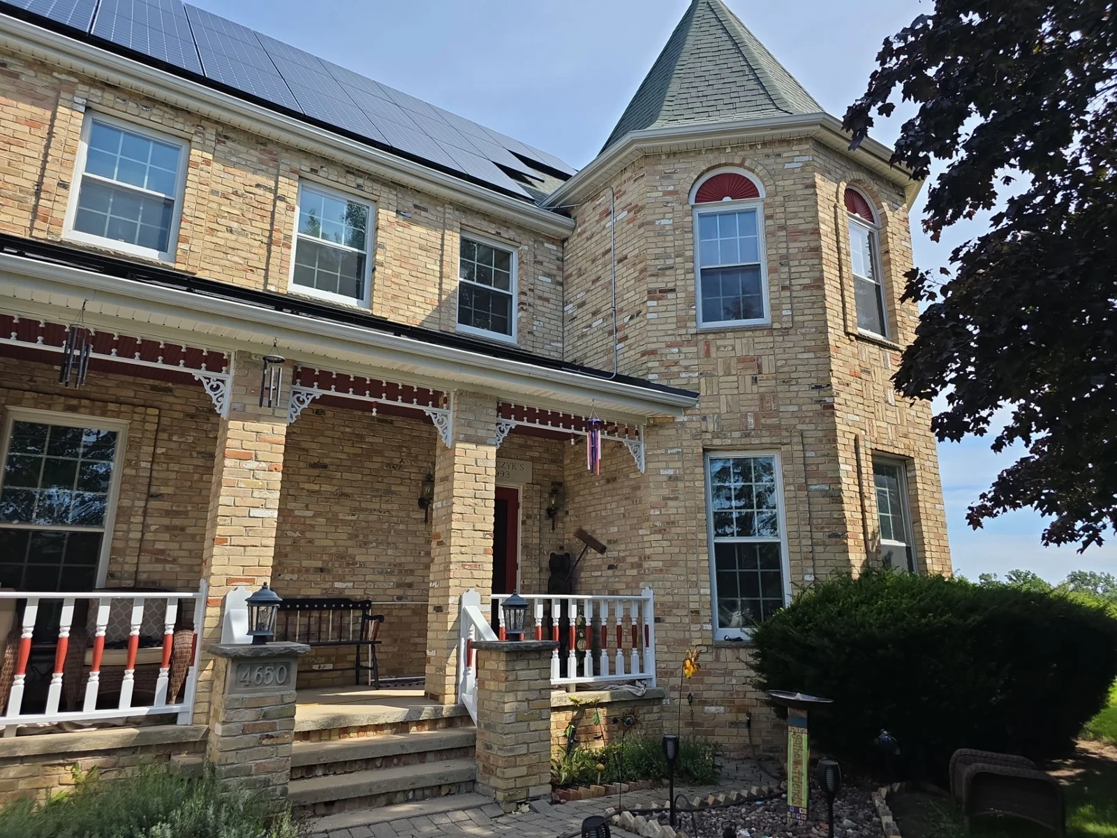 White porch railings and decorative trim with red accents at a Caledonia home.