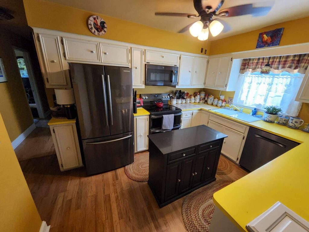 Cream kitchen cabinets, a dark island and yellow walls in a Brookfield home