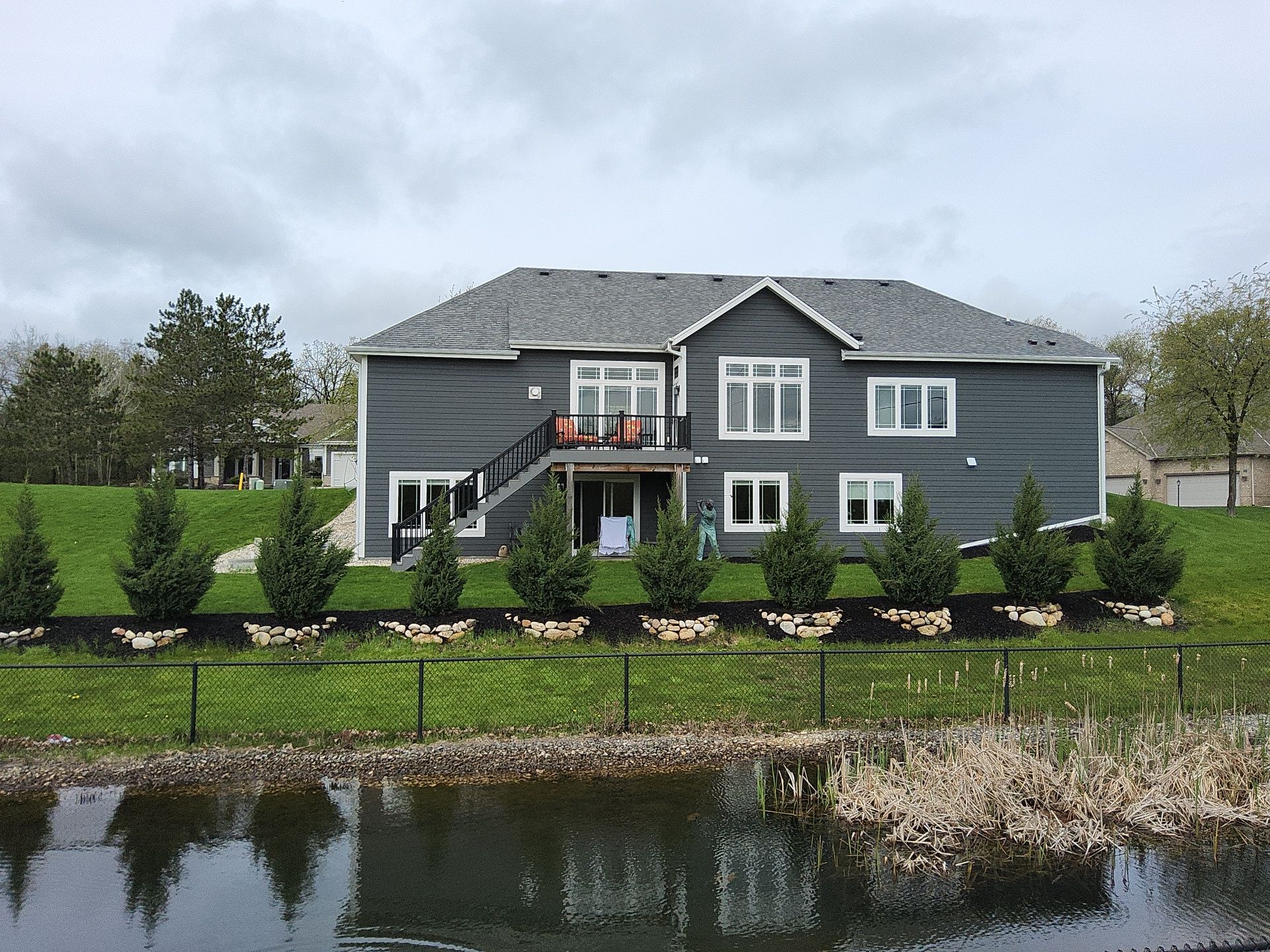 Rear home exterior and deck viewed across a pond in Wales, Wisconsin
