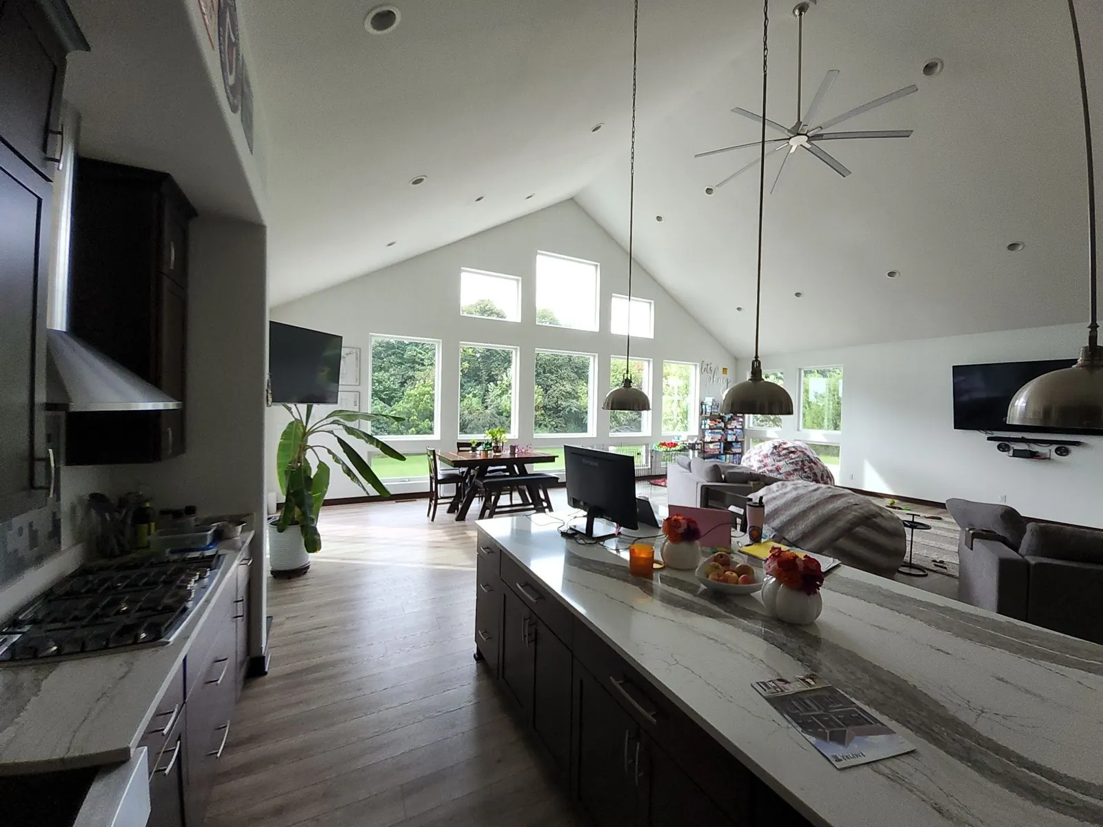 Delafield open-plan interior with a white vaulted ceiling, tall windows and a kitchen island.