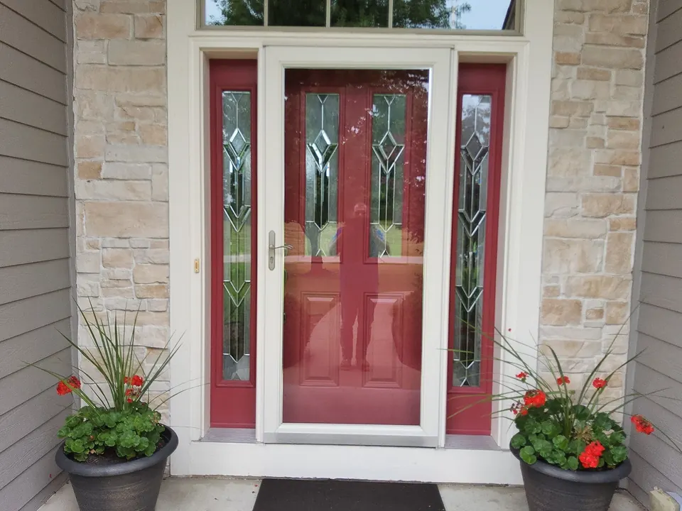Red front door with decorative glass, white trim and stone entry walls.