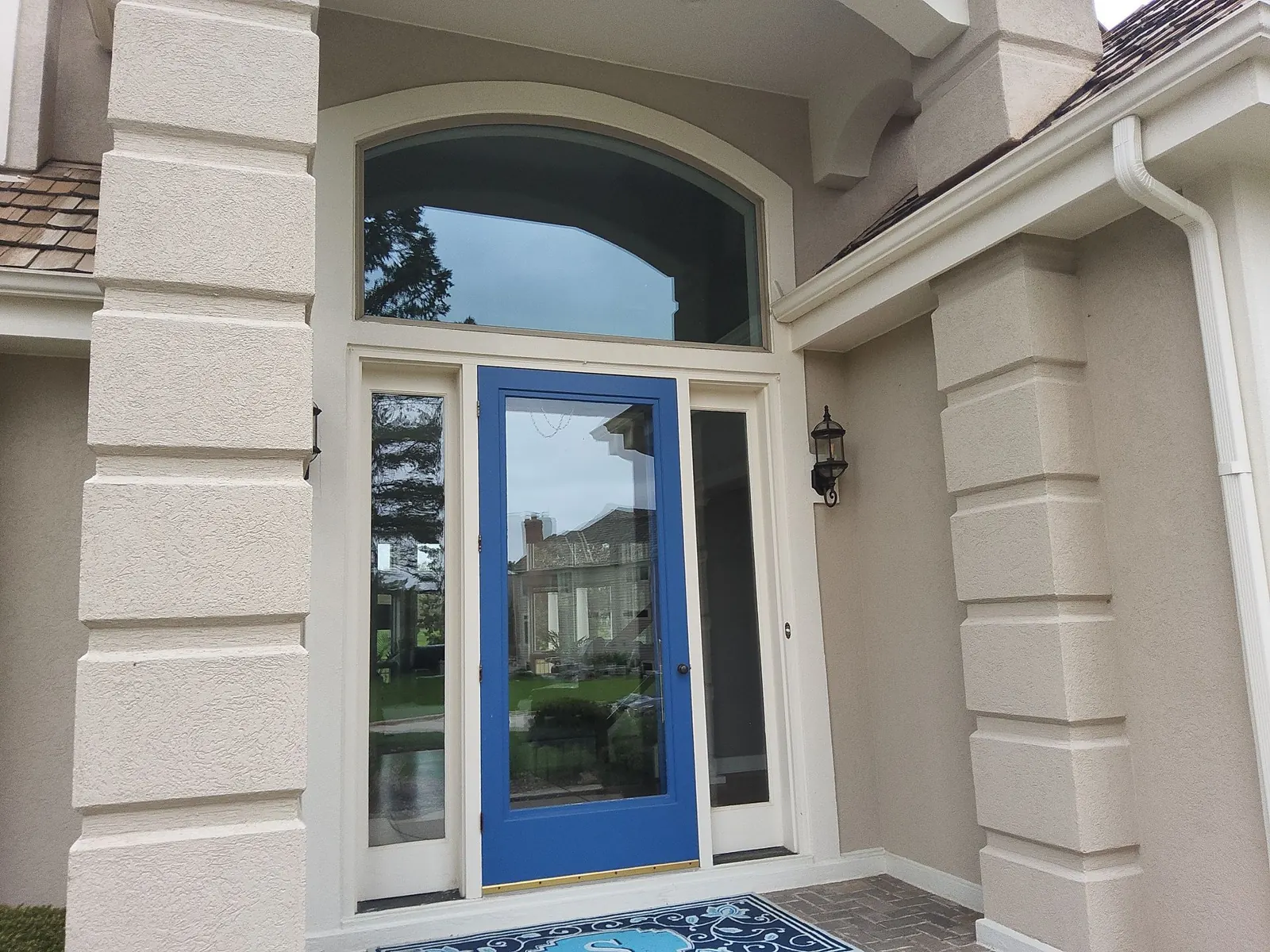 Blue glass entry door framed by cream trim and textured exterior columns.