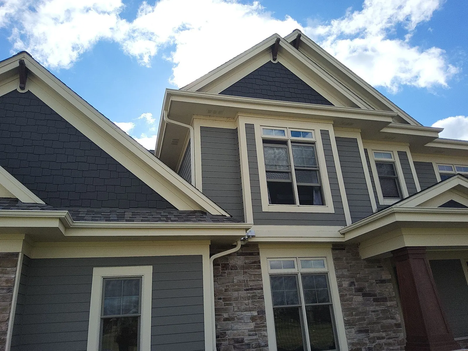 Gray siding, dark shingle gables and cream window trim on a Hartland home.