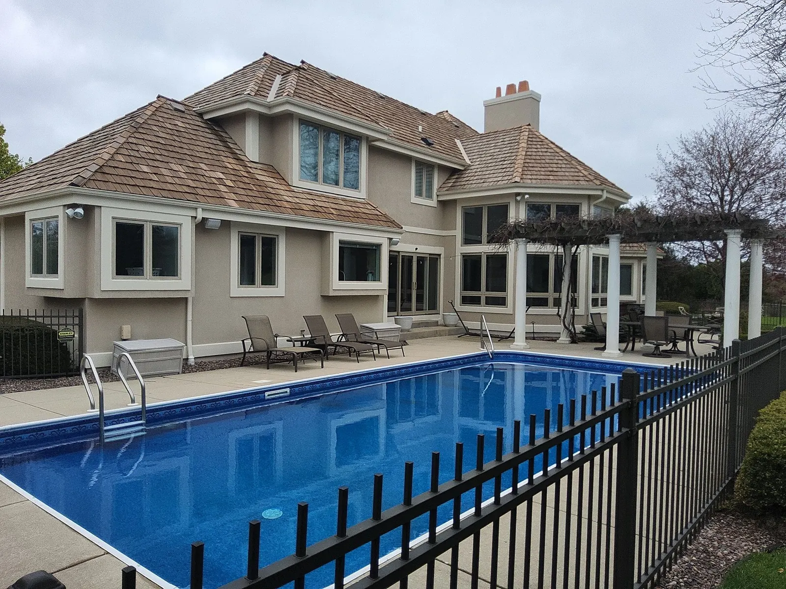 Light-colored Hartland house overlooking a swimming pool and pergola.