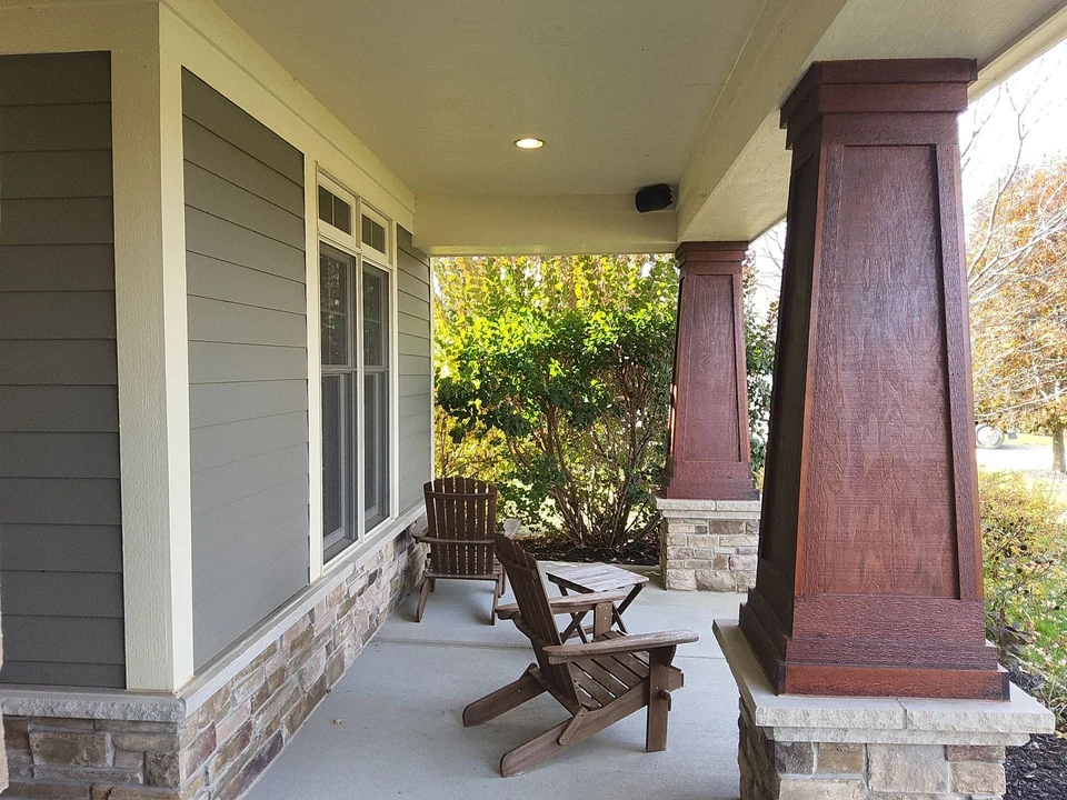 Covered porch with gray siding, white trim and stained wood columns