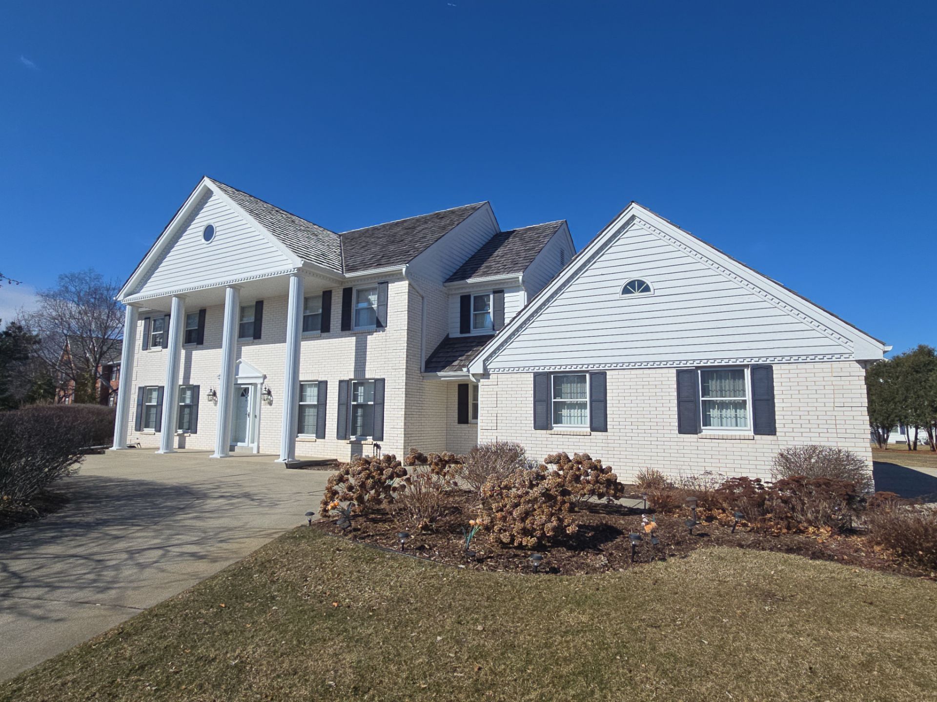 Mequon home with white columns, light siding and dark shutters