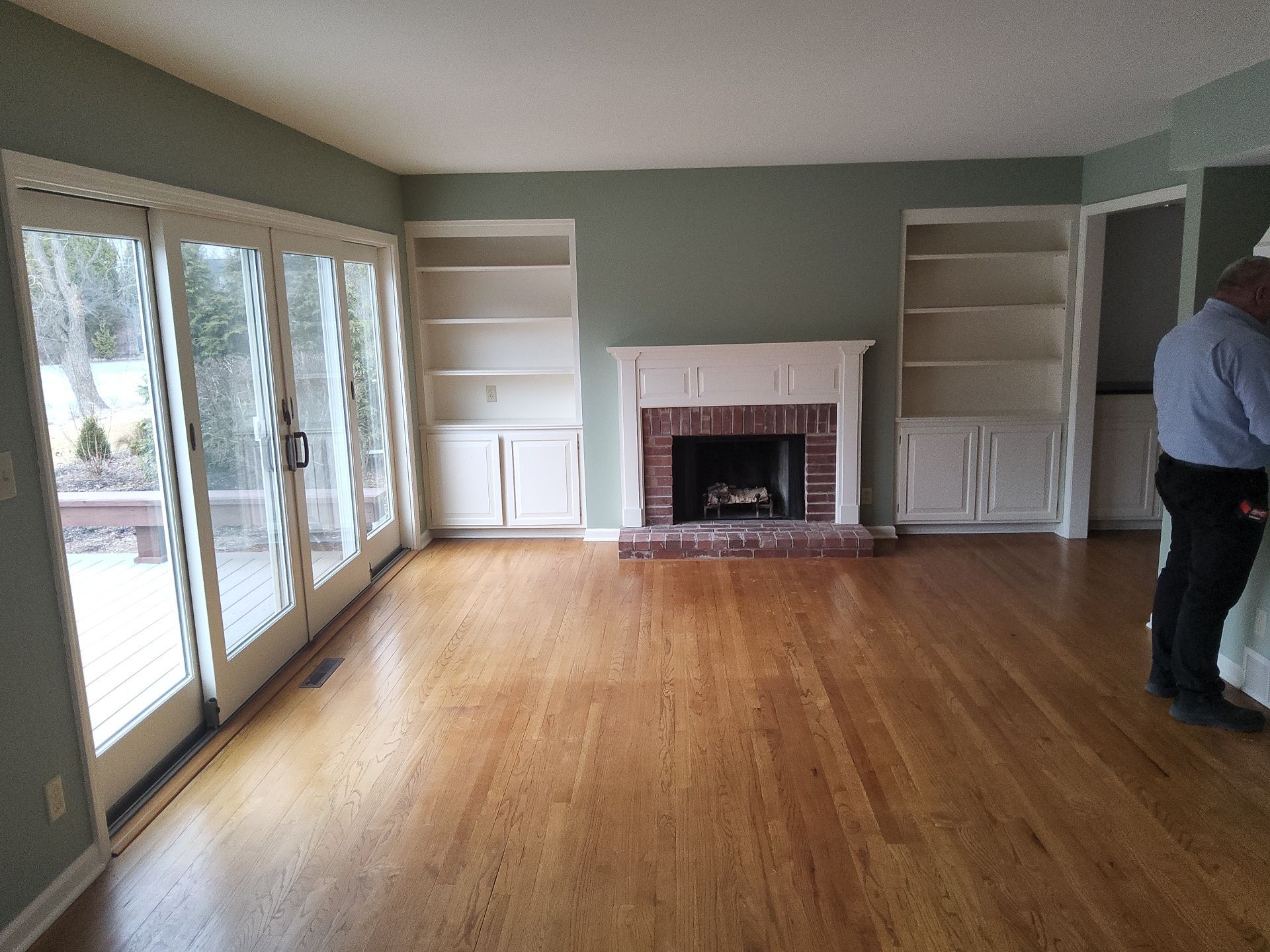 Mequon living room with green walls, white built-ins and a brick fireplace