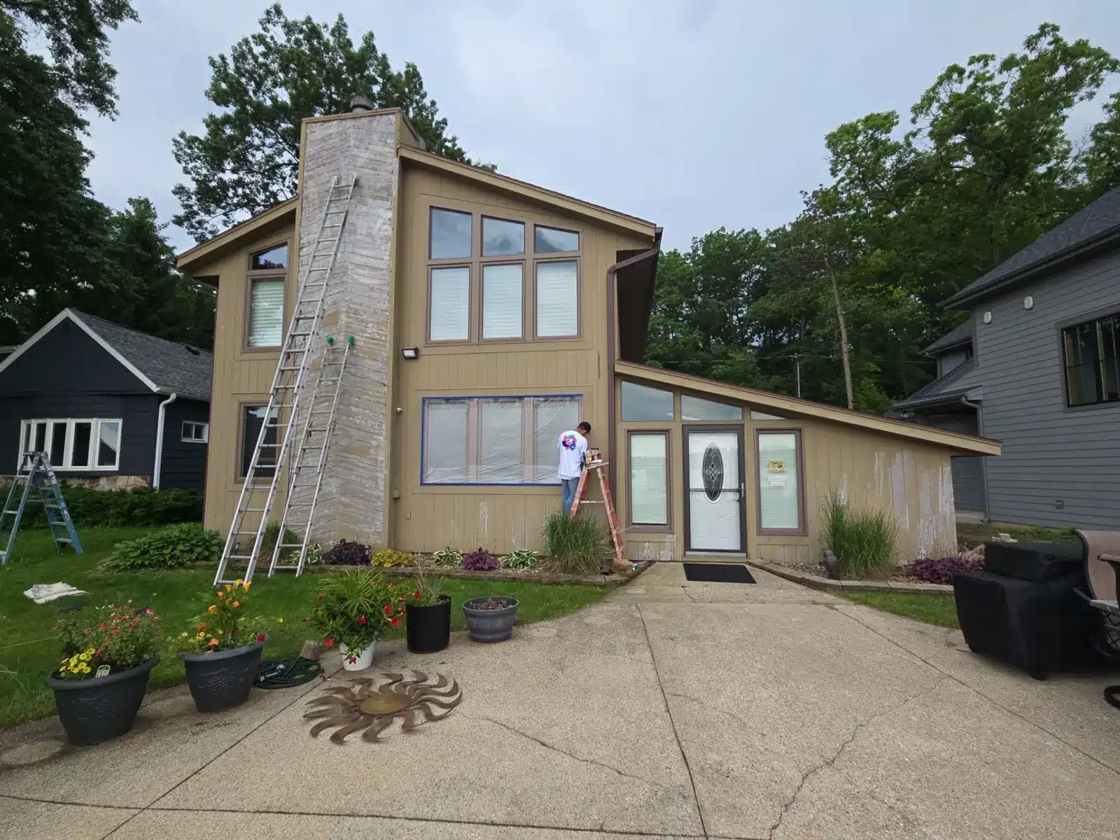 Exterior painting preparation with masked windows and ladders in Mukwonago