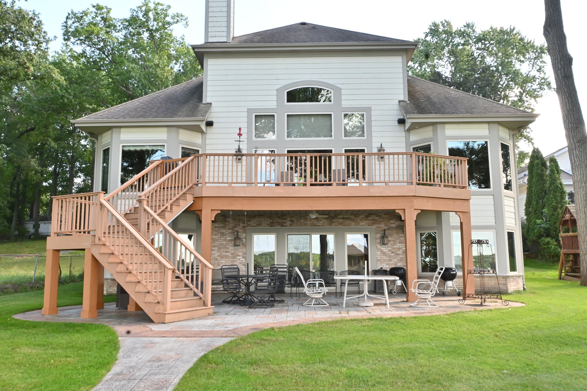 Backyard view of the completed Pewaukee home exterior with tall windows and an elevated deck