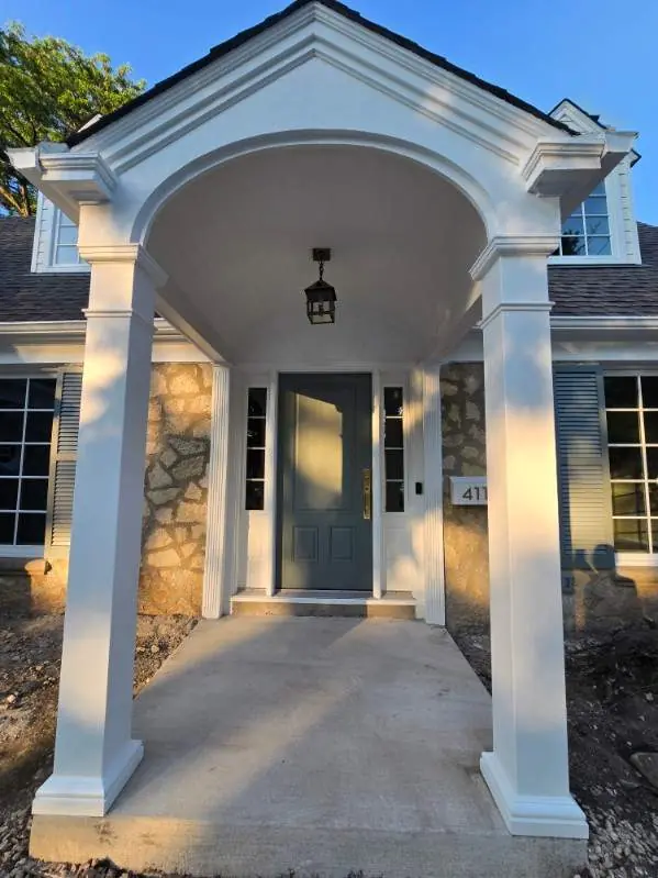 White portico columns and trim surrounding a gray front door in Shorewood