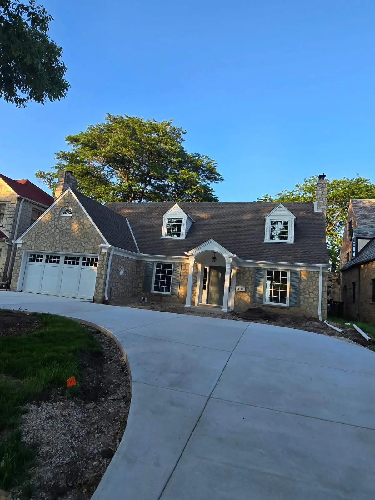 Stone home in Shorewood with white dormers, window trim and a covered front entry