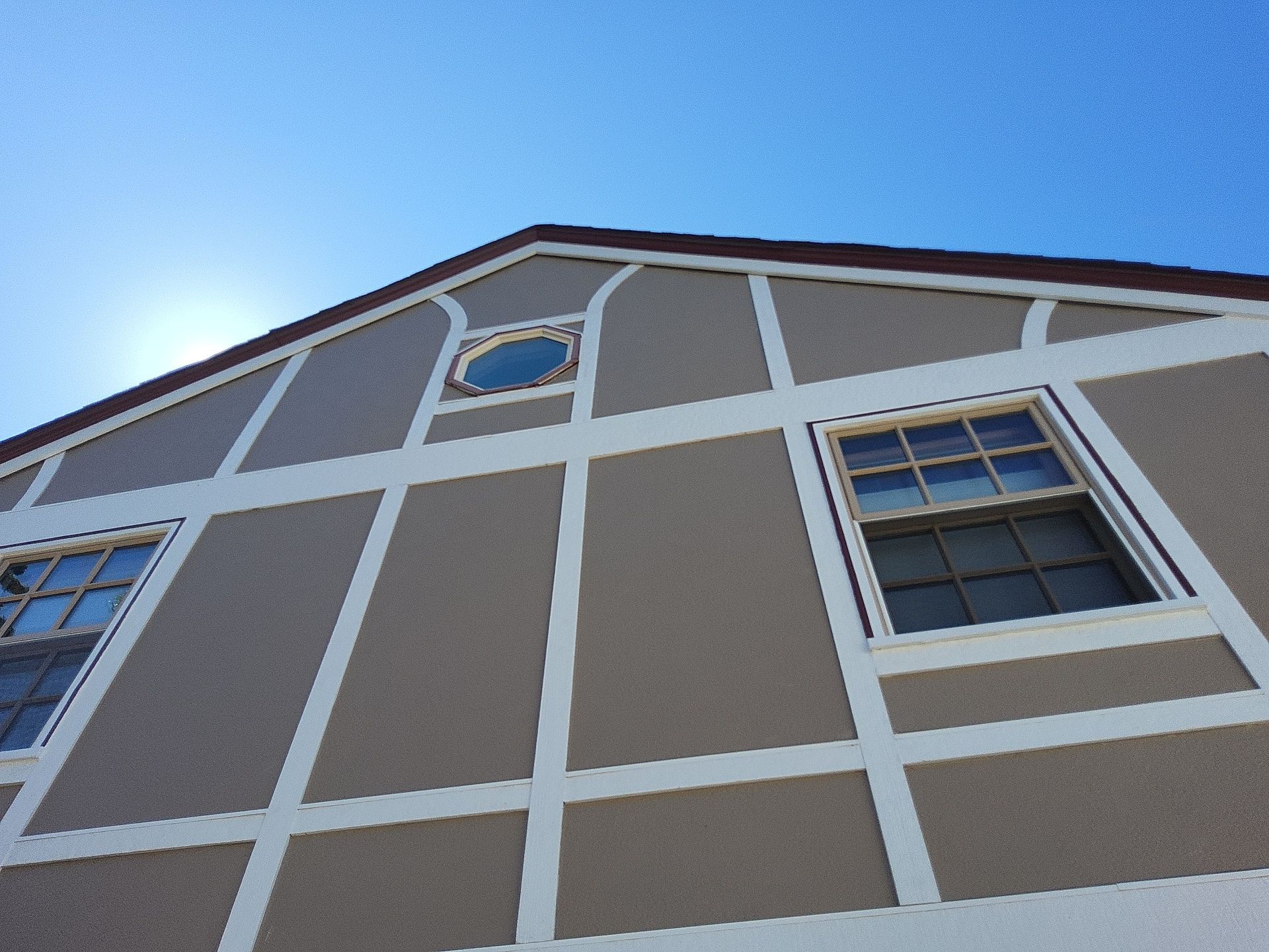 White gable trim and an octagonal window above tan exterior panels in Whitefish Bay