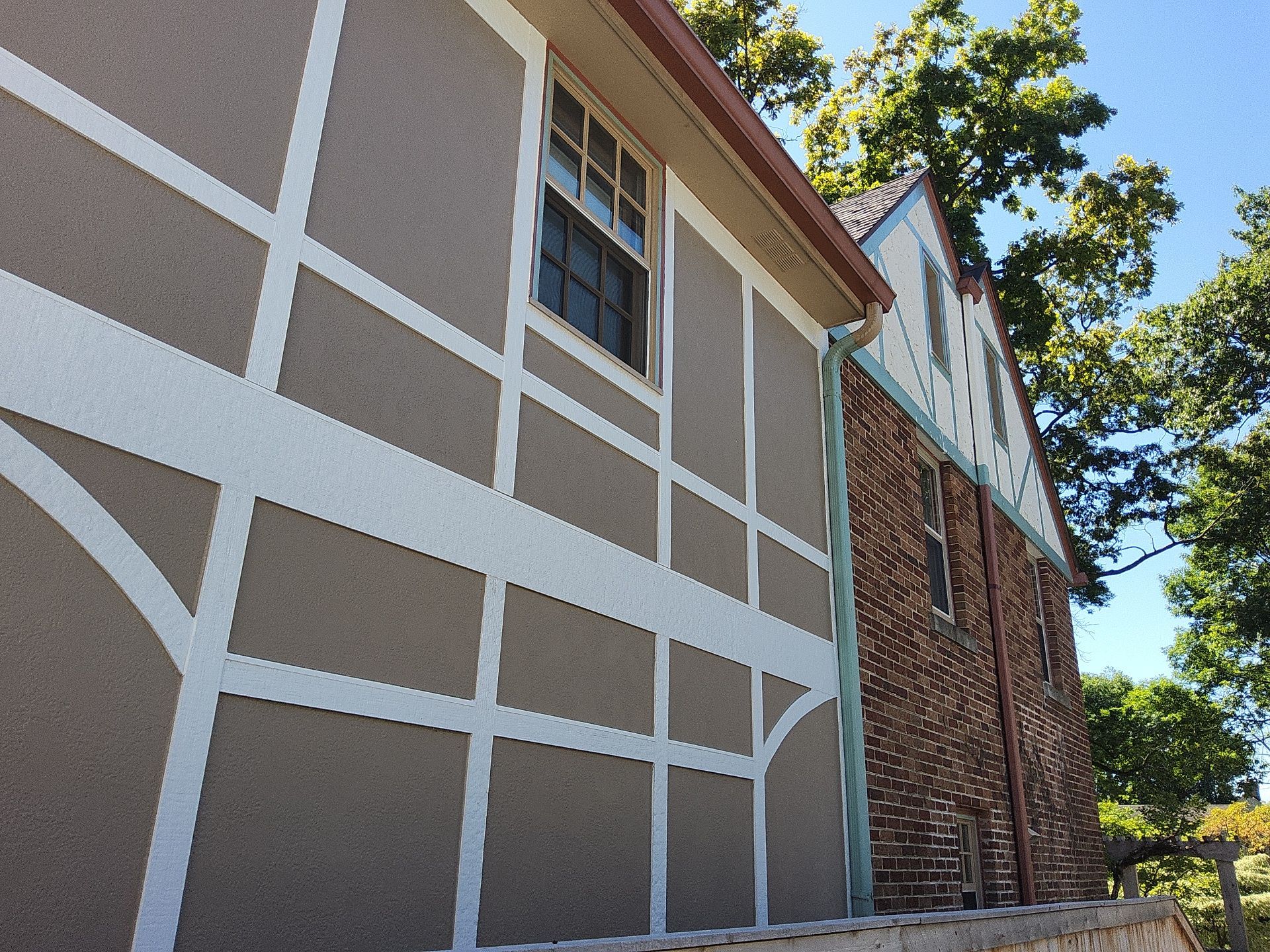 White decorative trim against tan exterior panels beside brickwork at a Whitefish Bay home