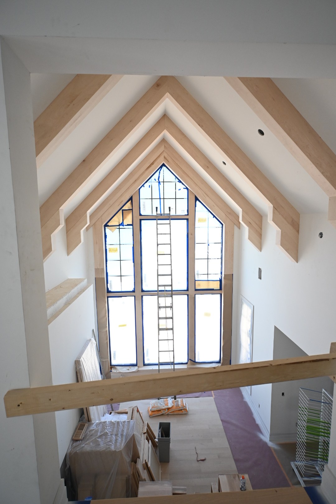 Vaulted room with exposed beams and a tall window during remodeling