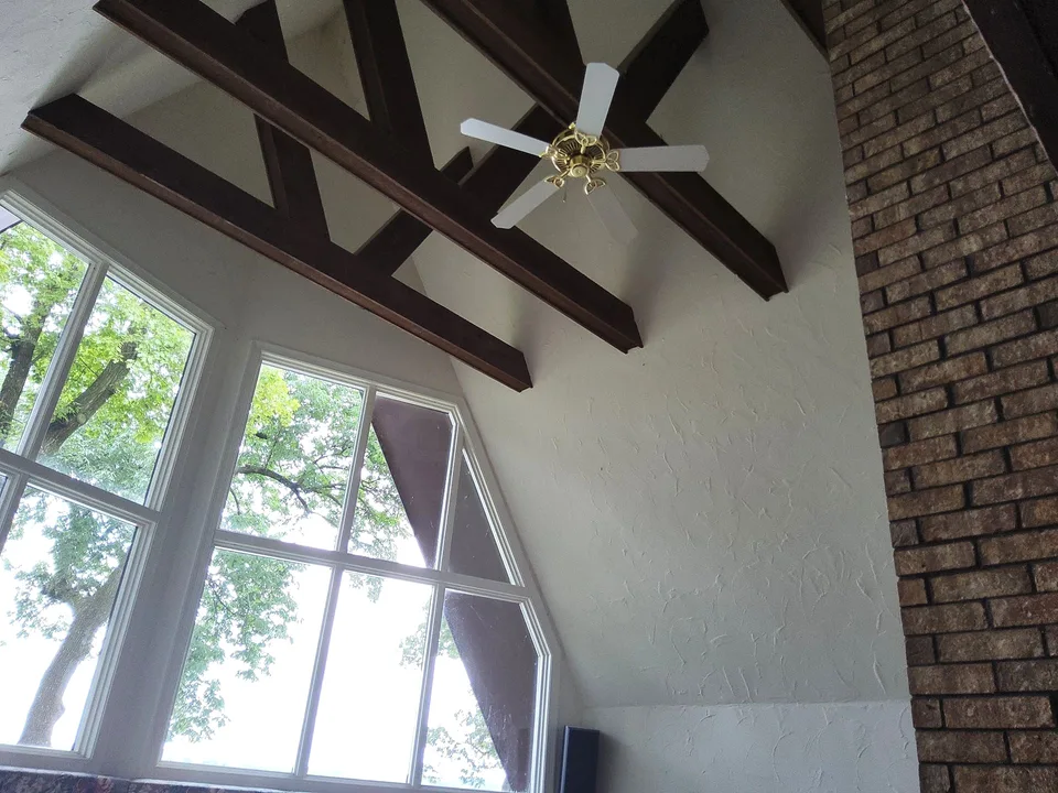 Light interior walls around tall windows and exposed wood ceiling beams