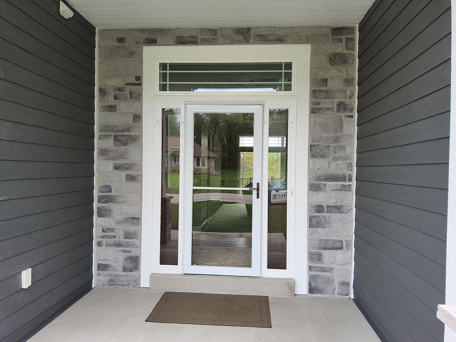 White entry trim framed by stone and gray siding at the Wales painting project