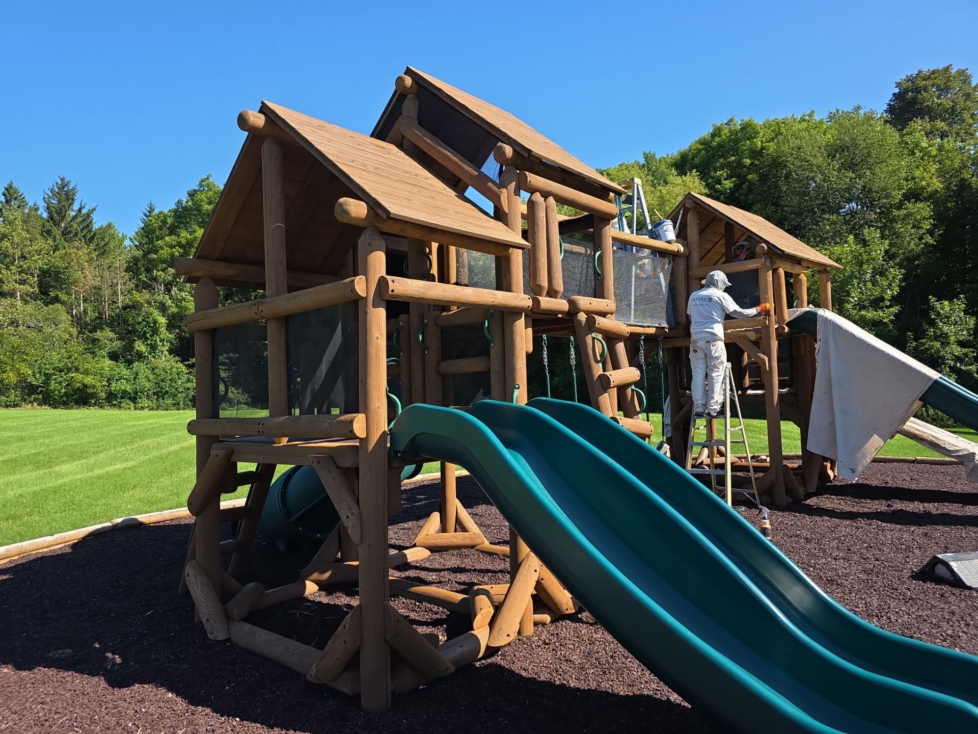 Empire Painting crew member working on a wooden playset in New Berlin