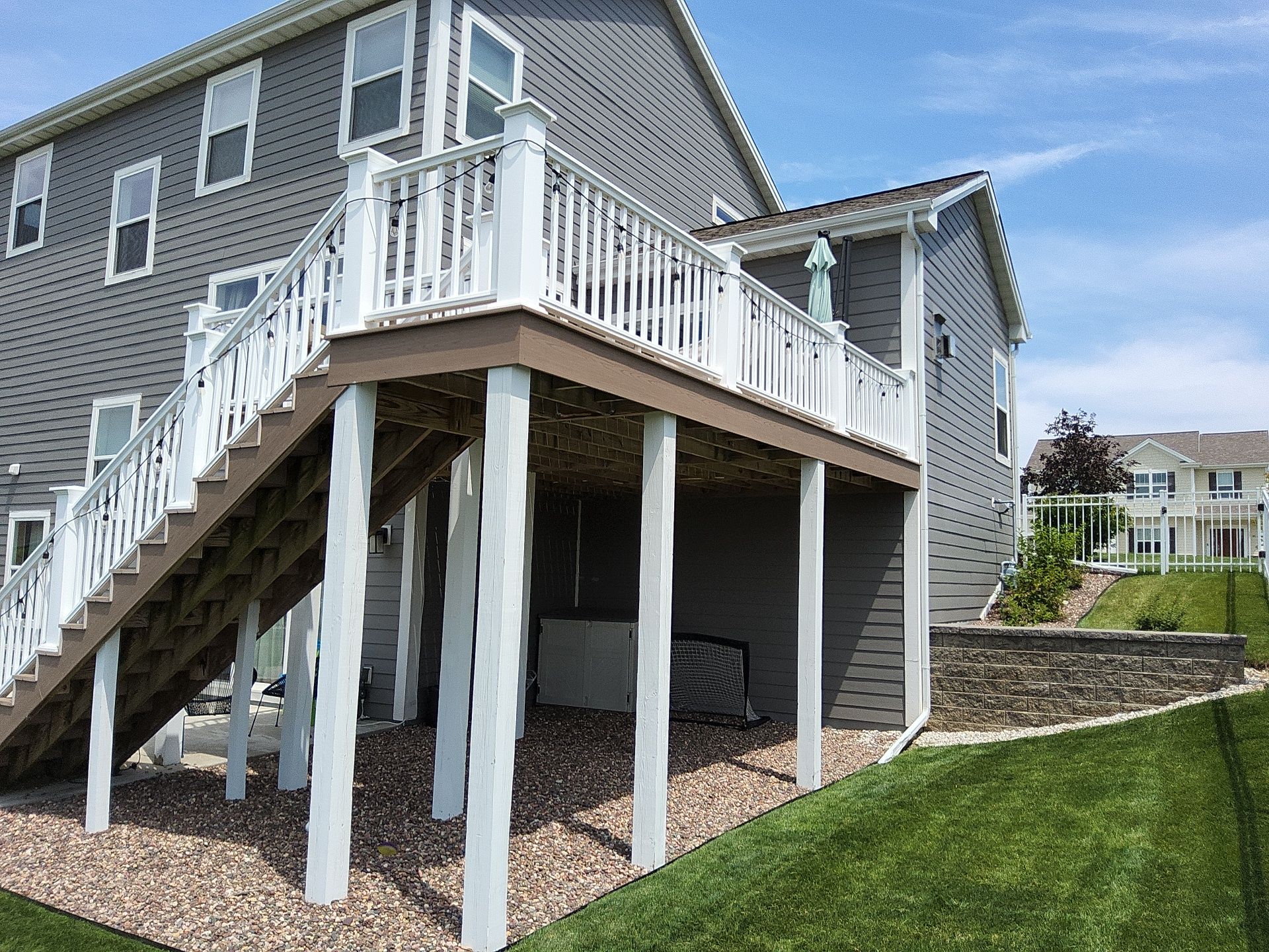 Raised deck with brown fascia, white posts and railings in Menomonee Falls