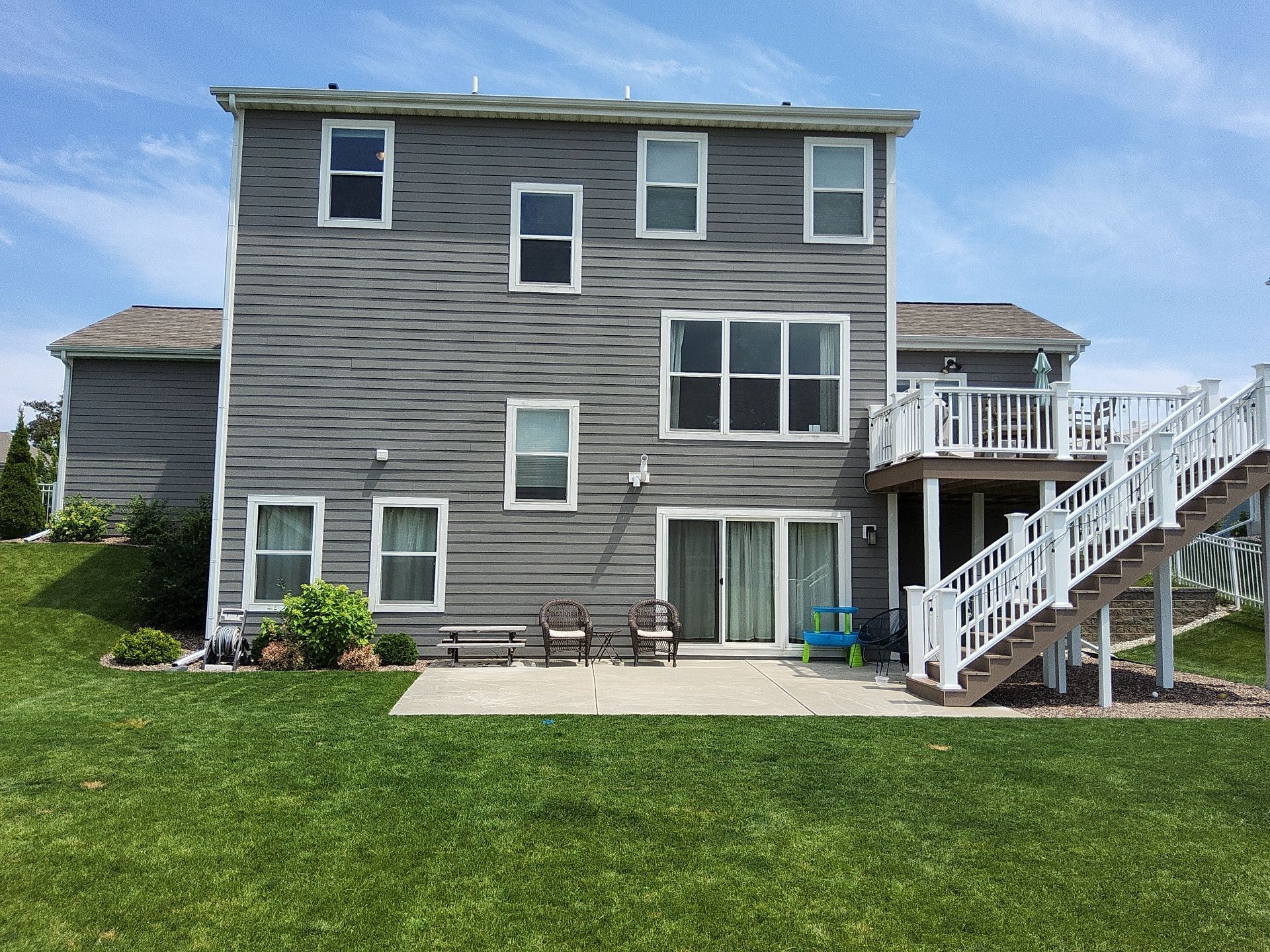 Rear elevation of a Menomonee Falls home with gray siding and a raised deck
