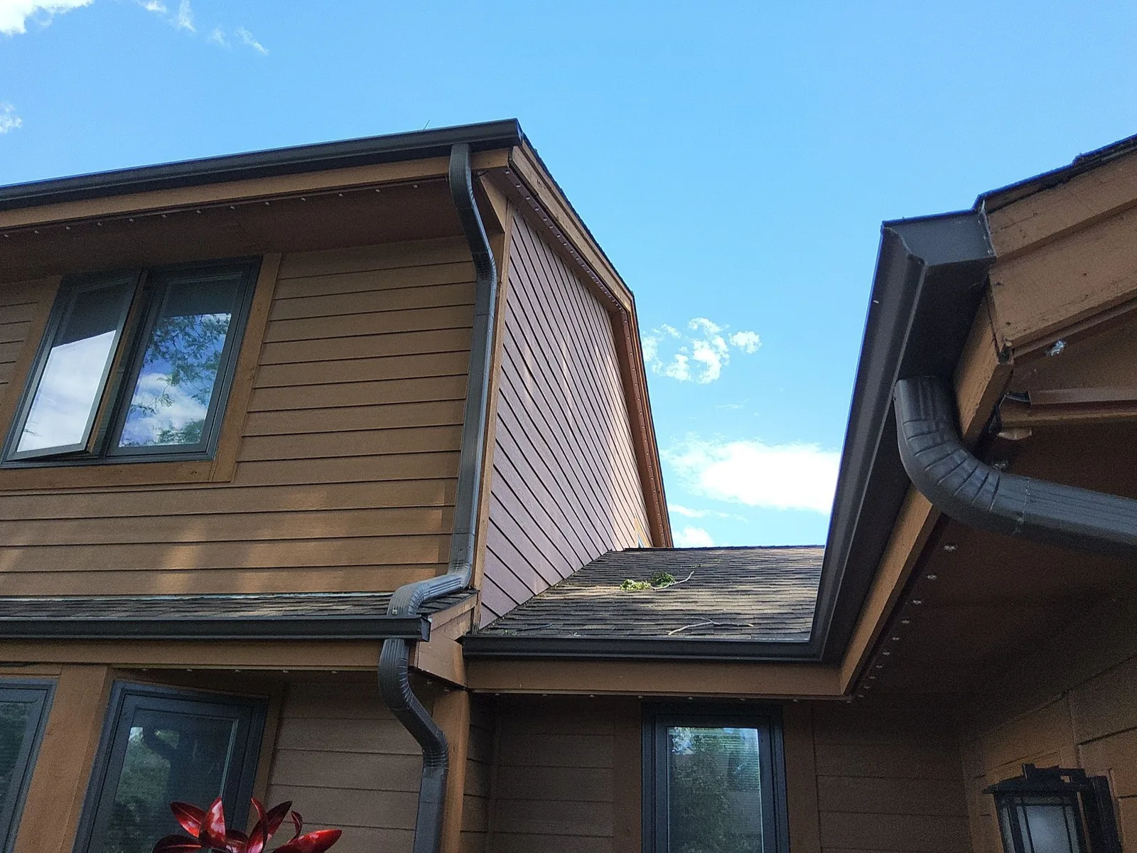 After: warm brown exterior siding and trim along the rear rooflines