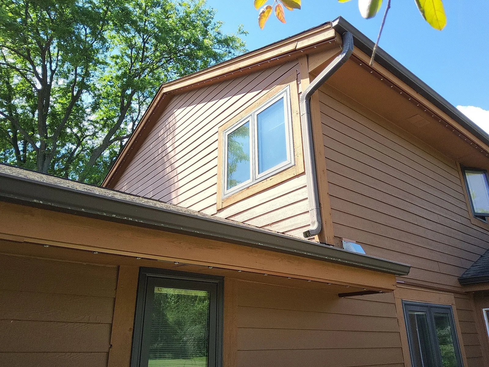 Painted siding and cedar trim on the upper gable of a Mequon home