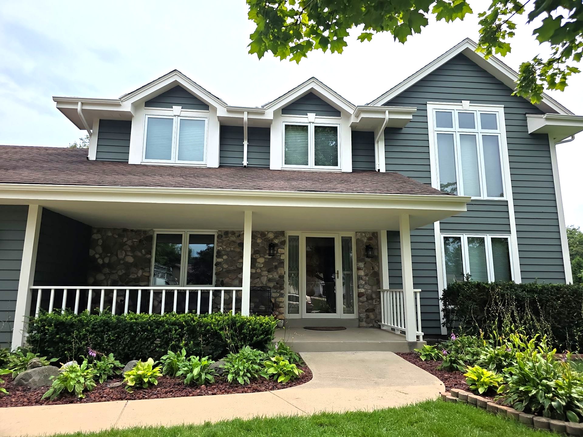 Gray siding, light trim and covered front porch at the New Berlin home