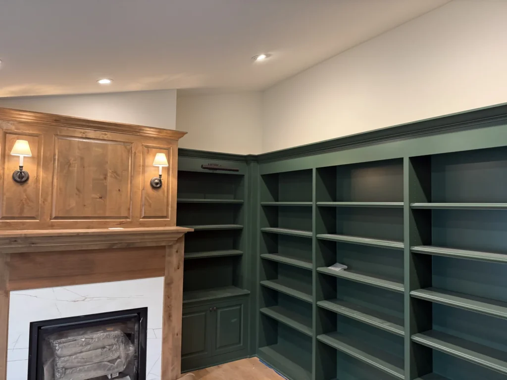 Deep green built-in shelves beside a natural wood fireplace surround.