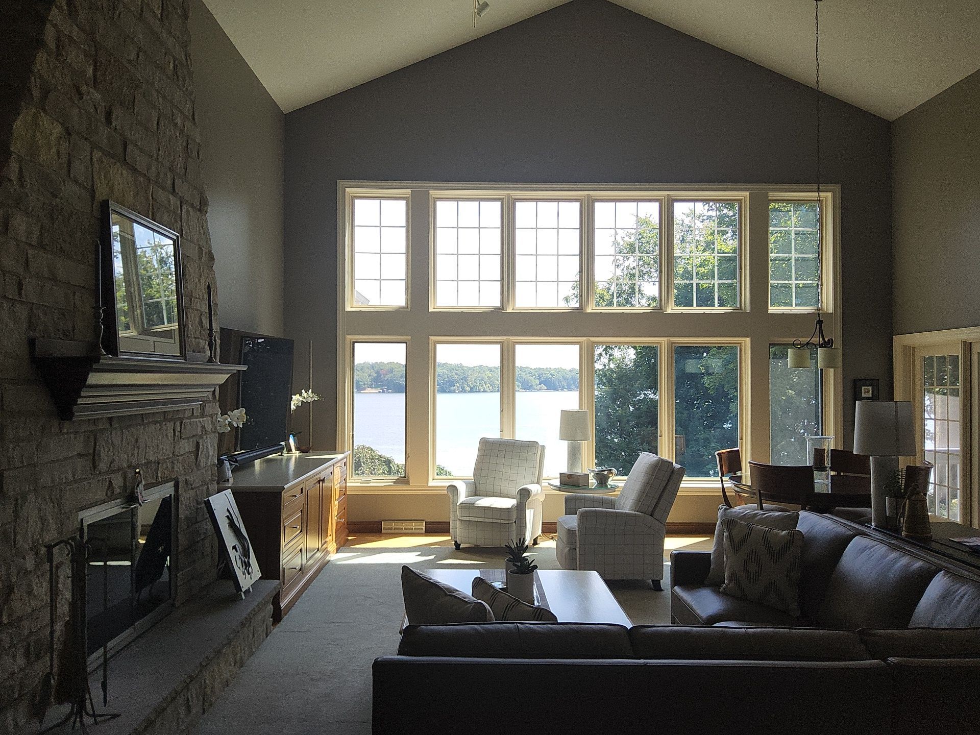 Lake-view living room with tall windows and a stone fireplace