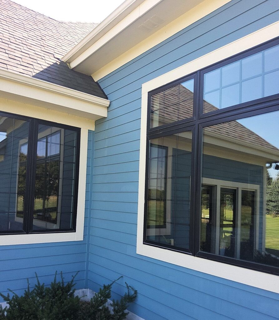 Blue exterior siding with crisp white trim and black windows in Oconomowoc