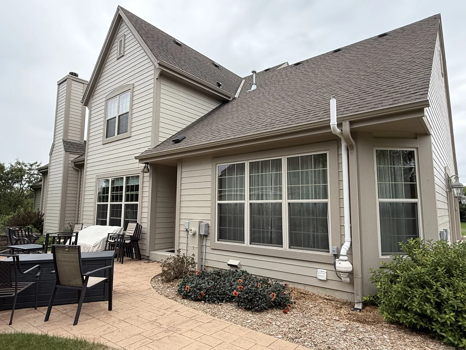 Rear elevation of a Pewaukee home with light lap siding, taupe window trim and a patio