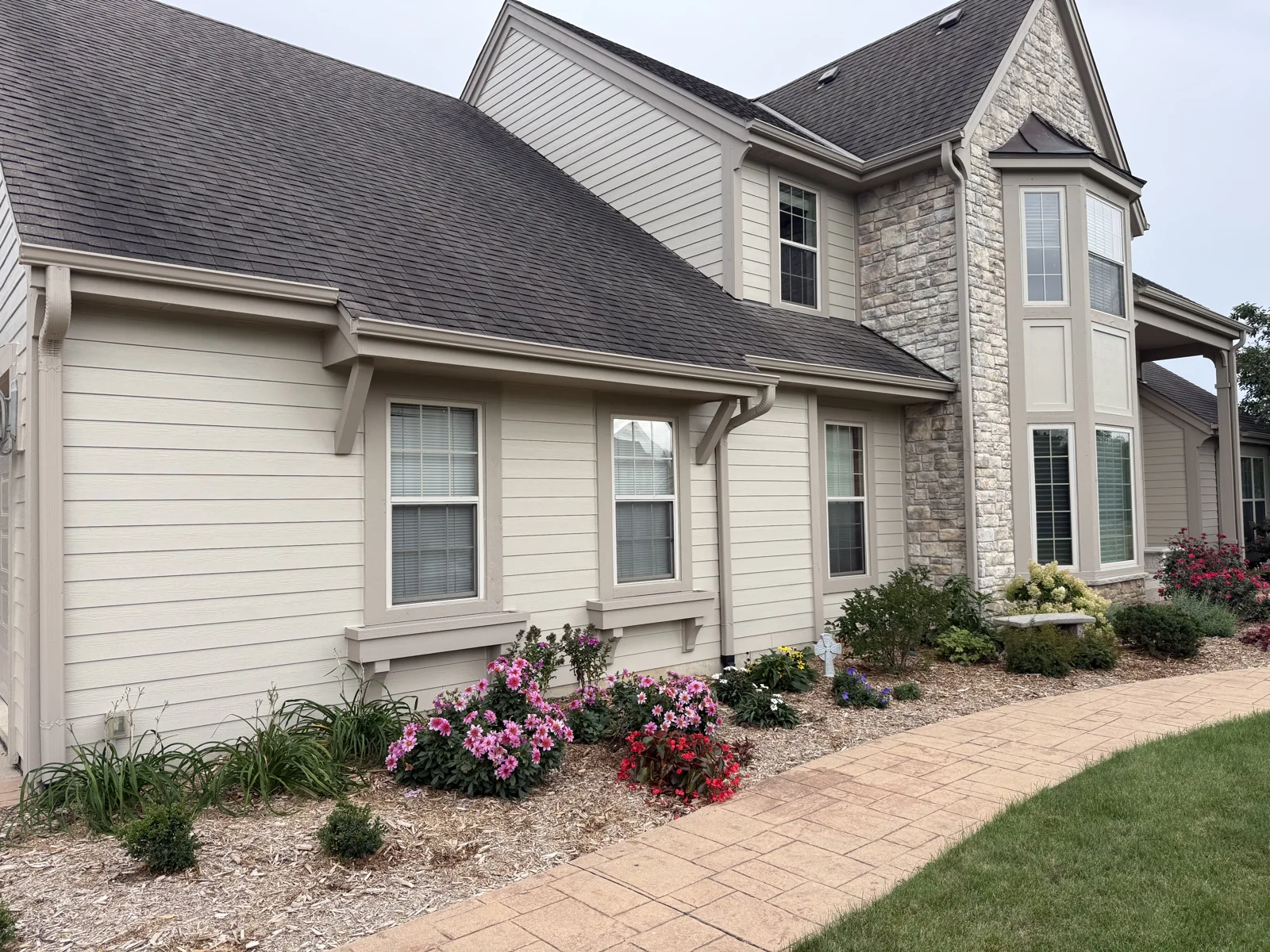 Pewaukee home exterior showing light siding, taupe window trim and a stone bay window