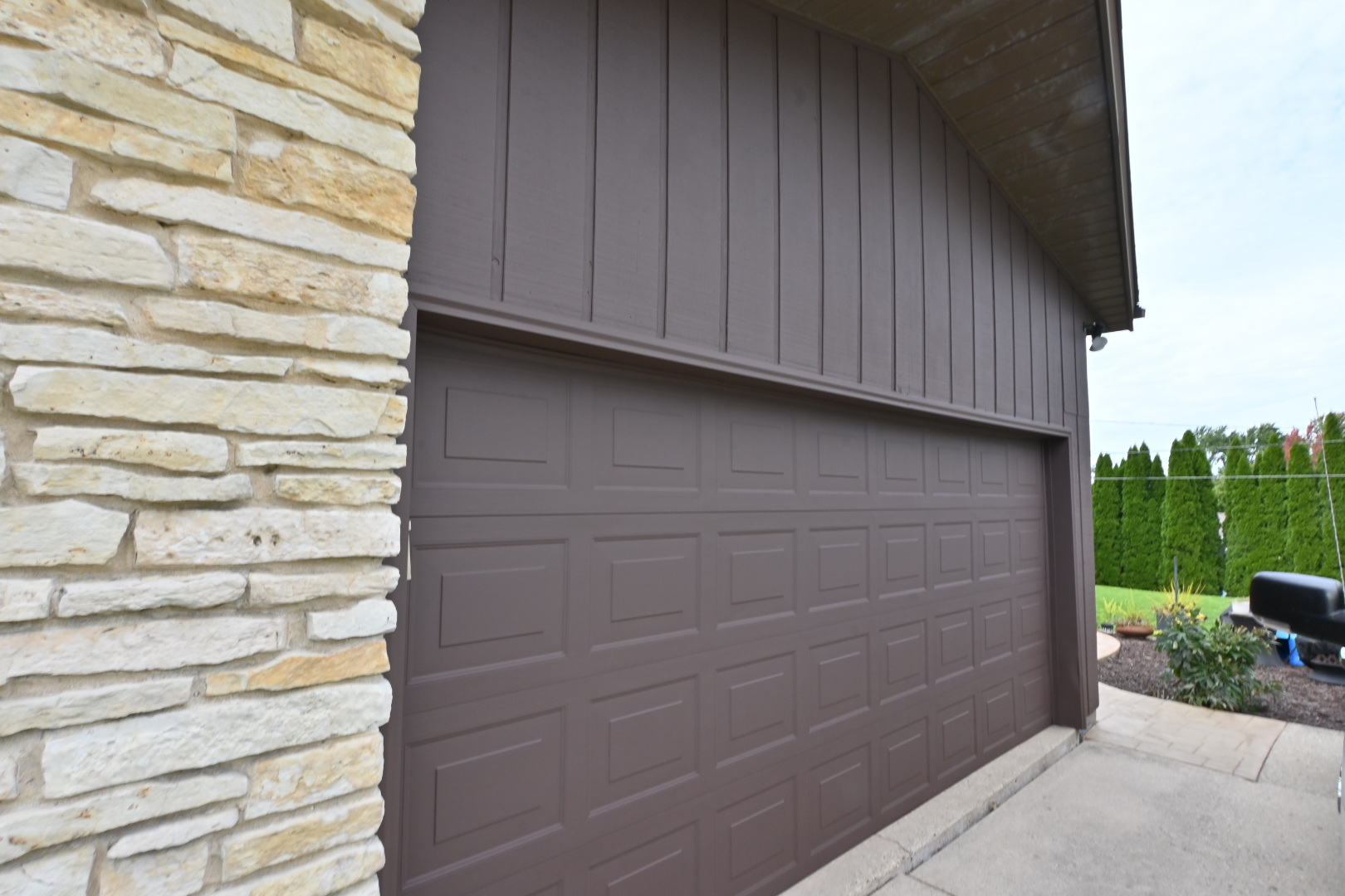 Fresh brown cedar siding and painted garage door on a Waukesha home with stone accents