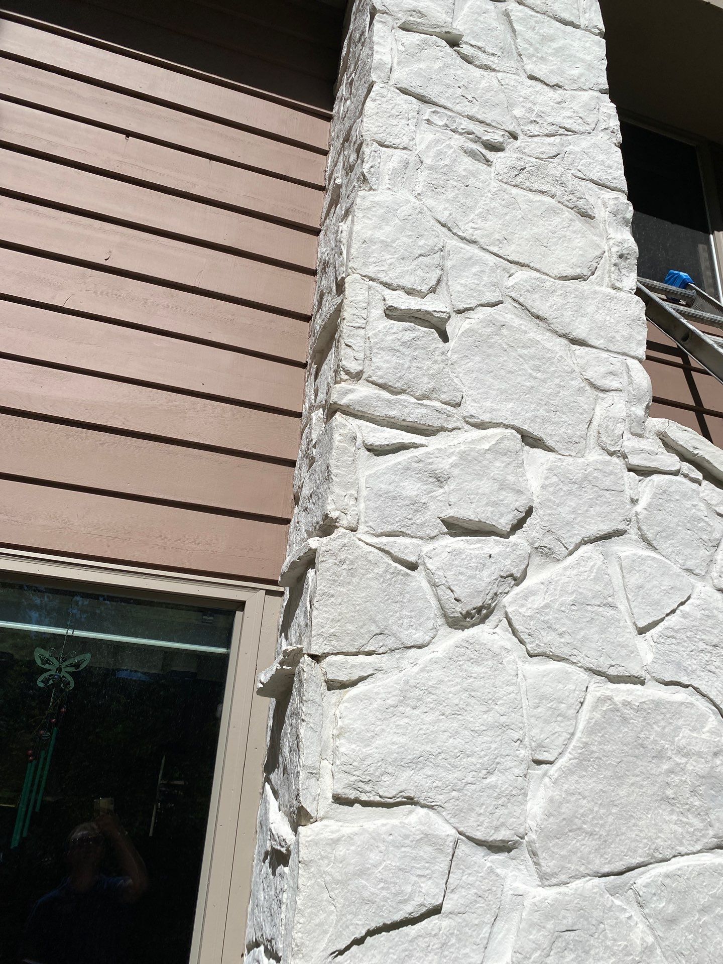 White painted stone chimney beside wood siding in Colgate
