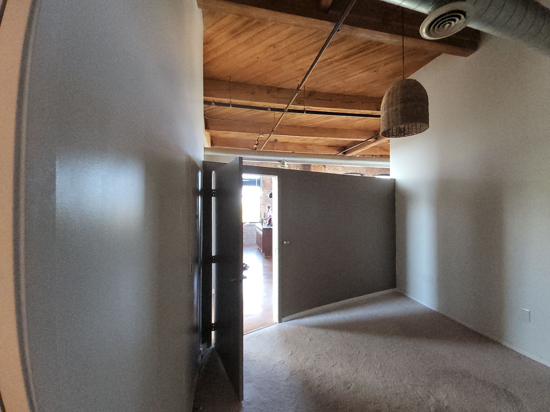 Neutral painted room beneath exposed wood ceilings and ductwork