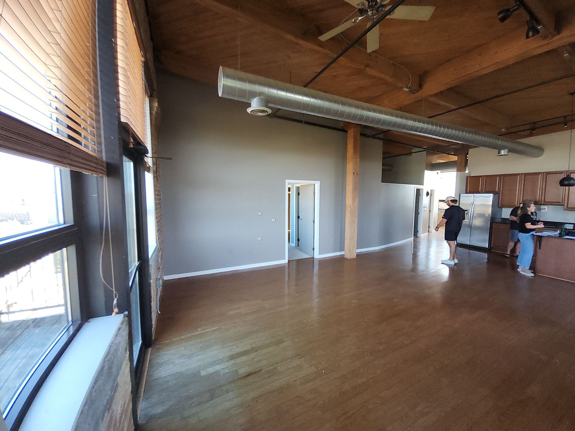 Open Milwaukee loft living area with freshly painted walls, white trim, timber beams and exposed brick