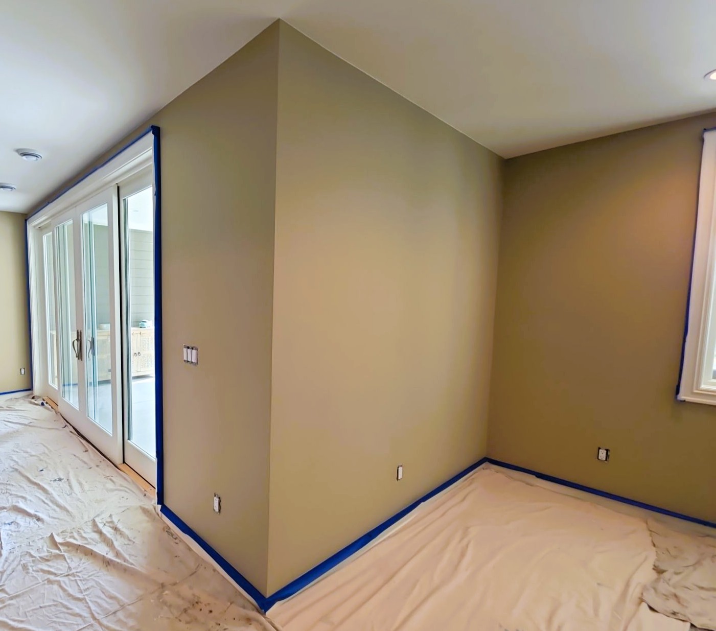 Interior painting in progress with neatly taped trim and clean drop cloths protecting the floors