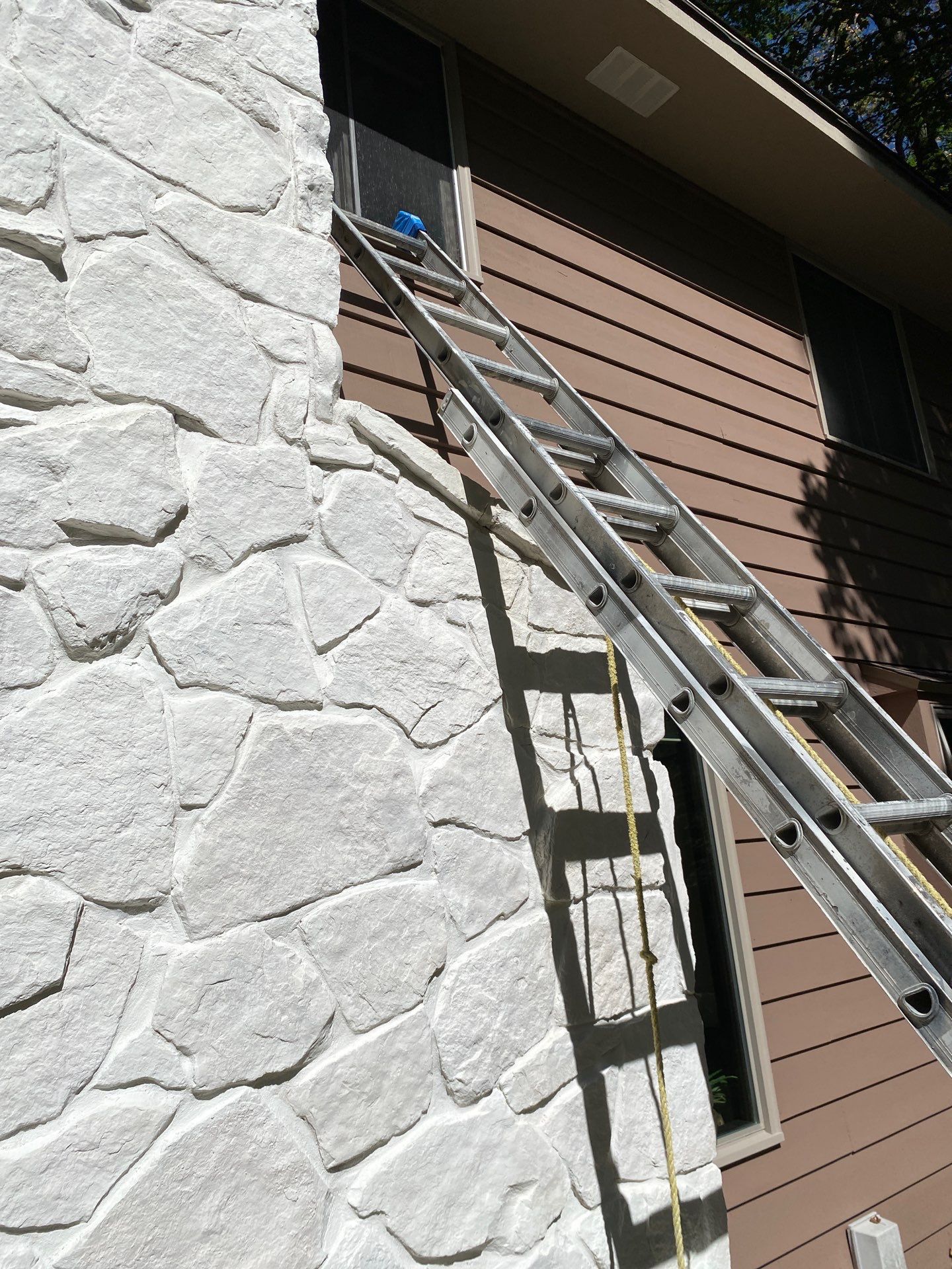 Painted white stone chimney and wood siding detail in Colgate