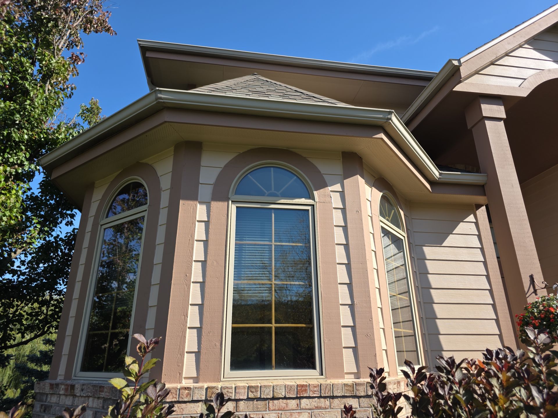 Arched windows, contrasting trim and light siding at a Hartland exterior project